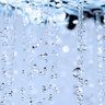 Wassertropfen fallen in einer sanften Bewegung, während sie im Licht funkeln und eine ruhige Atmosphäre schaffen.