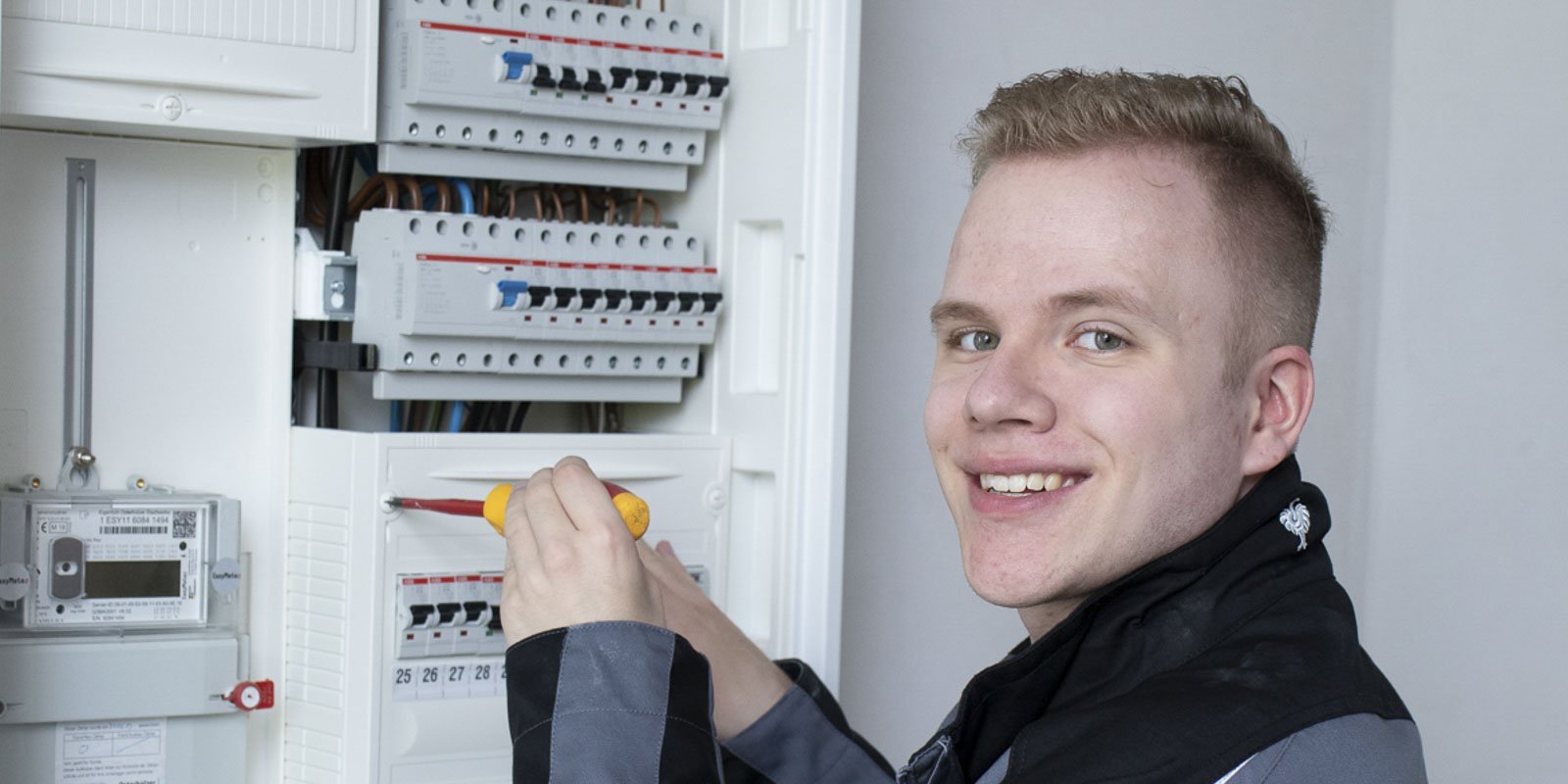Ein Elektroniker der an einem Verteilerkasten schraubt